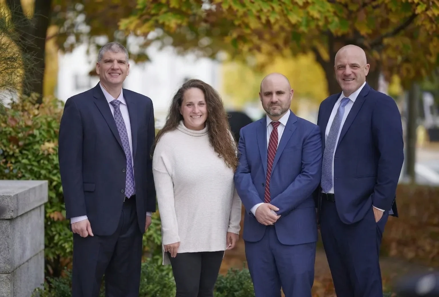 The attorneys and paralegal of Combies Hanson, P.C. standing outdoors in autumn